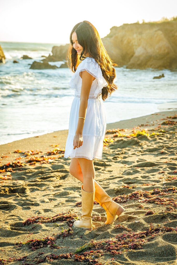 High school senior walking along the tide at Moonstone Beach in Cambria, California, during a sunset portrait session.
