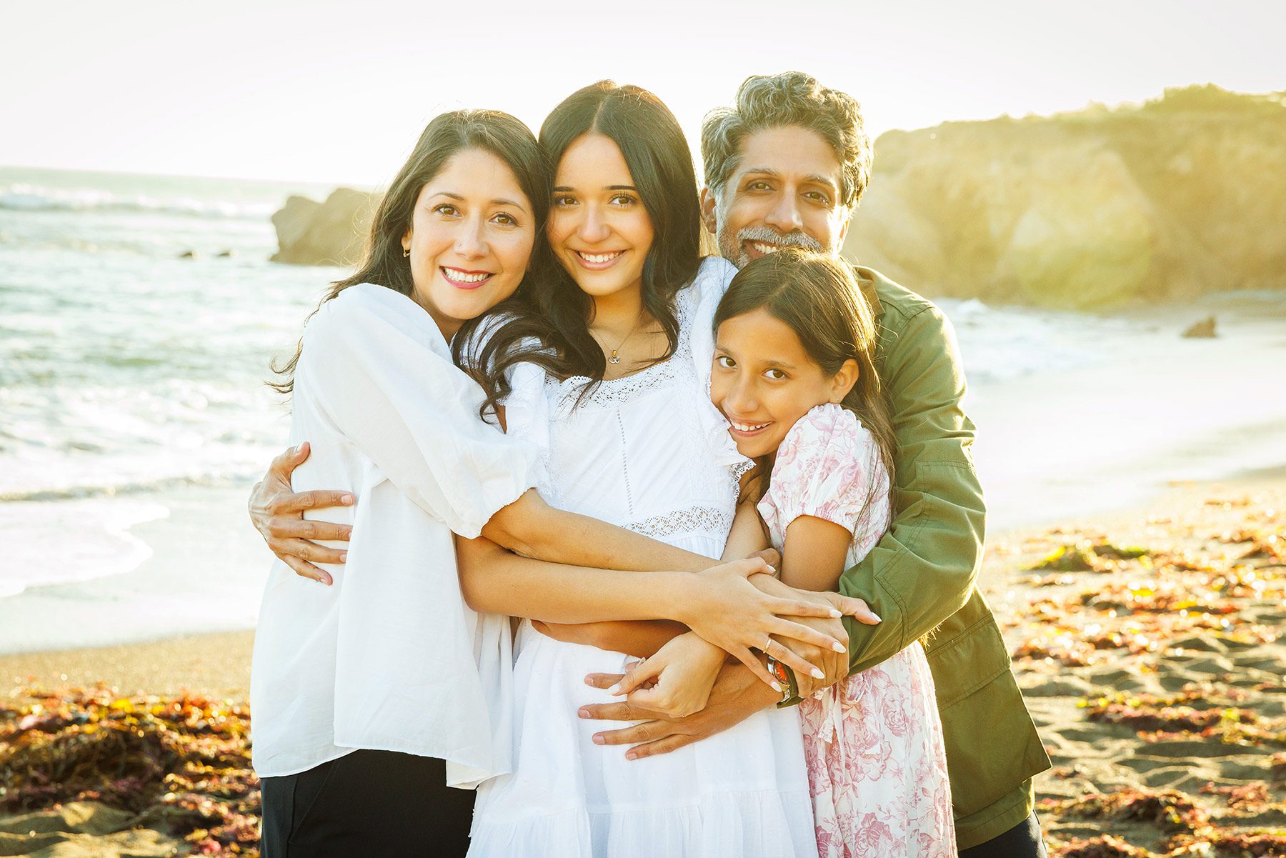 Candid moment of a mother hugging her daughters during a family sunset photo session on the Central Coast.