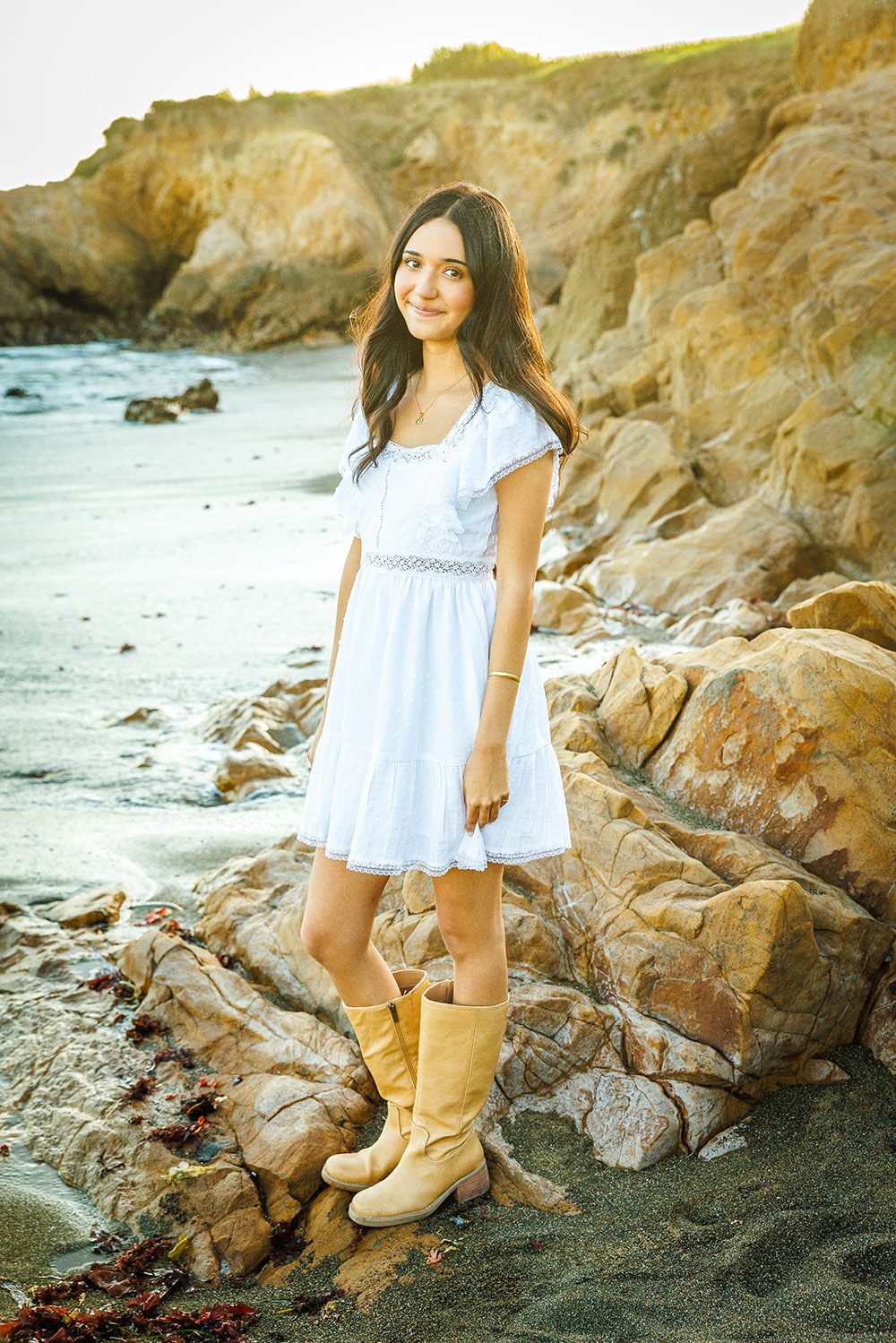 Senior girl posing against the rugged rock formations and coastal cliffs of Moonstone Drive in Cambria.