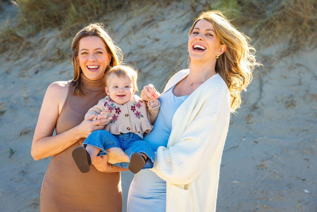 Sisters and baby sharing a joyful moment during a Morro Bay family session